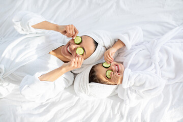 Top view of mother and daughter laying on bed