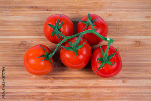 Top view of red tomatoes on branch on wooden surface