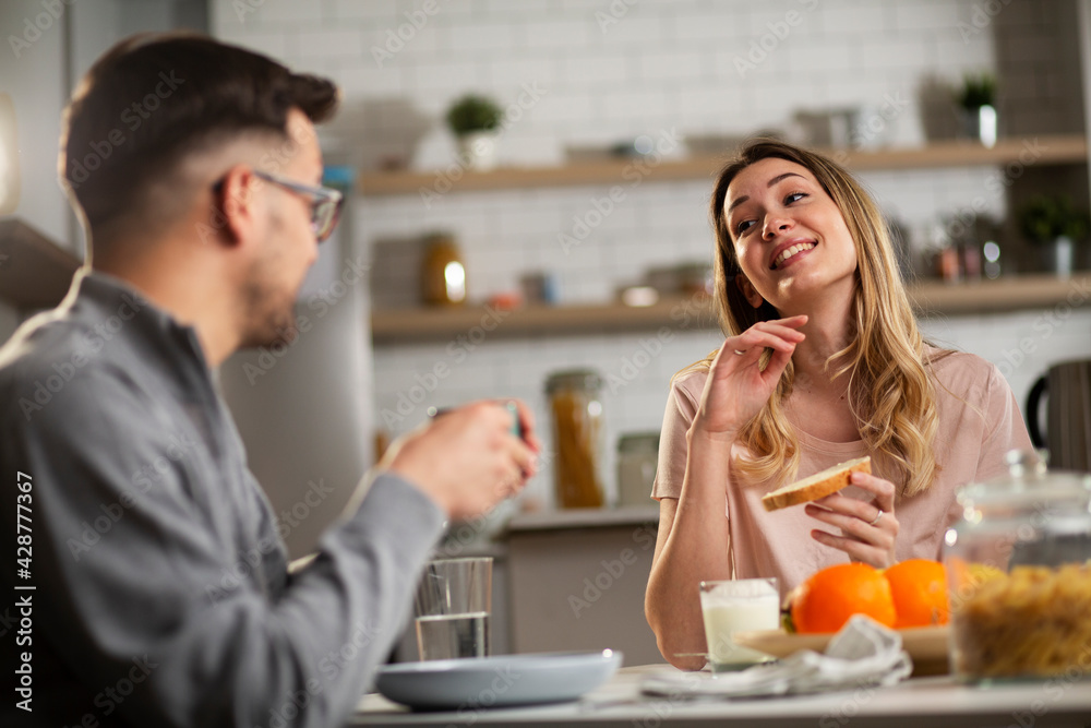 Beautiful young woman enjoying in breakfast with boyfriend. Happy young couple drinking coffee and eating sandwich at home.. Beautiful young woman enjoying in breakfast with boyfriend. Happy young couple drinking coffee and eating sandwich at home..