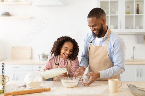 Happy afro family preparing dough together in kitchen