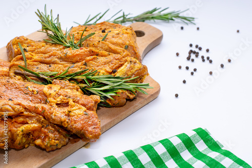 Raw marinated meat, steaks with rosemary and pepper on a white background