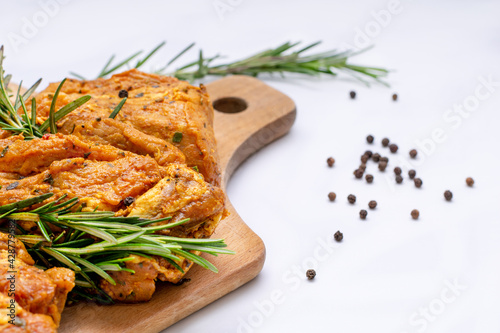 Raw marinated meat, steaks with rosemary and pepper on a white background
