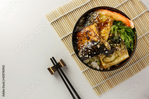 Saba Don. Grilled saba rice with teriyaki sauce and seaweed salad in wood bowl and wood chopstick on white table background. Traditional Japanese breakfast. Popular meal of Japan and Asian. Close up. photo