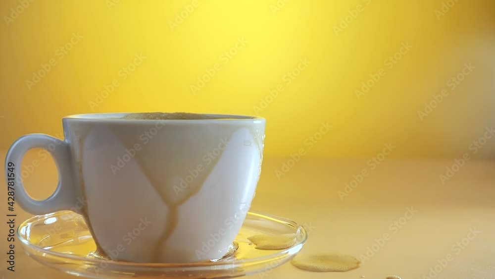 A piece of sugar slowly falls into a cup of coffee, causing a large splash. Slow motion.