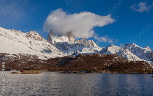Panorama image of  a mountain range with the summit of the Cerro Fitzroy shrouded in clouds with the lake 'Laguna Capri' in the foreground  © Chris
