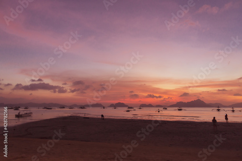 Scenic sunset on tropical beach. Aerial view of dramatic evening sky and boats silhouettes. Picturesque landscape of Palawan island, Philippines. Tropical seascape in night dusk. Summer travel. 
