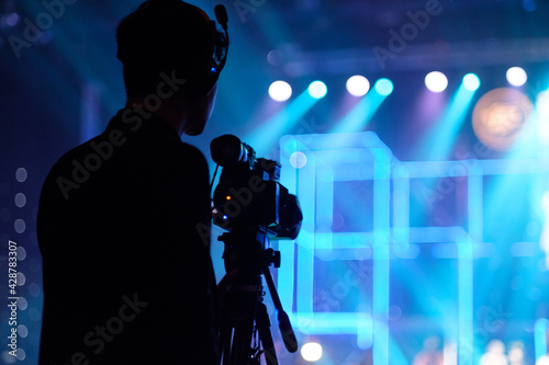Blurred photo of Cameraman silhouette in concert hall.