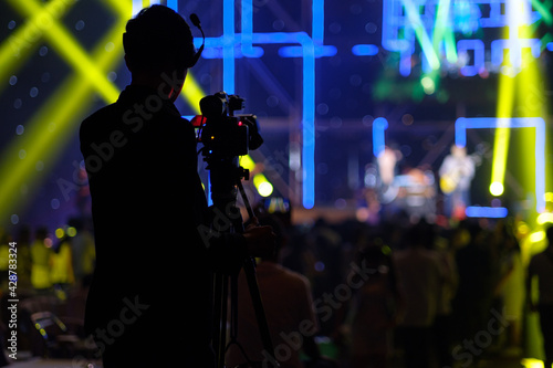 Blurred photo of Cameraman silhouette in concert hall.