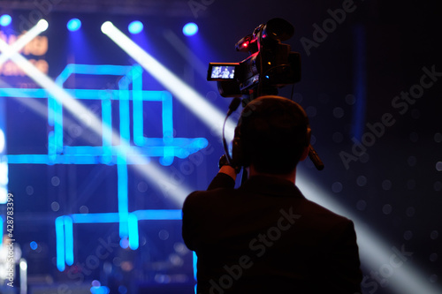 Blurred photo of Cameraman silhouette in concert hall.