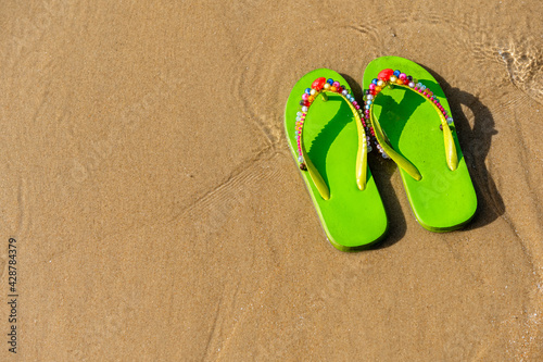 Green decorated flip flops on the beach