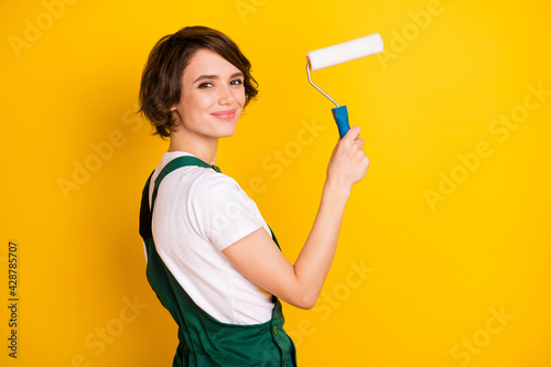 Fototapeta Naklejka Na Ścianę i Meble -  Photo of happy lovely pretty smiling cheerful woman builder painter hold roller isolated on yellow color background