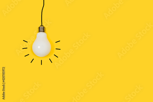 Bombilla de luz colgante sobre un fondo amarillo liso y aislado. Vista de frente y de cerca. Copy space photo