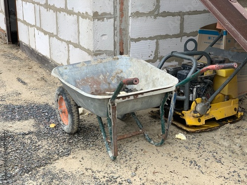 Construction gray cement cart close up. A gray cart with dry cement mortar stands on the grass.