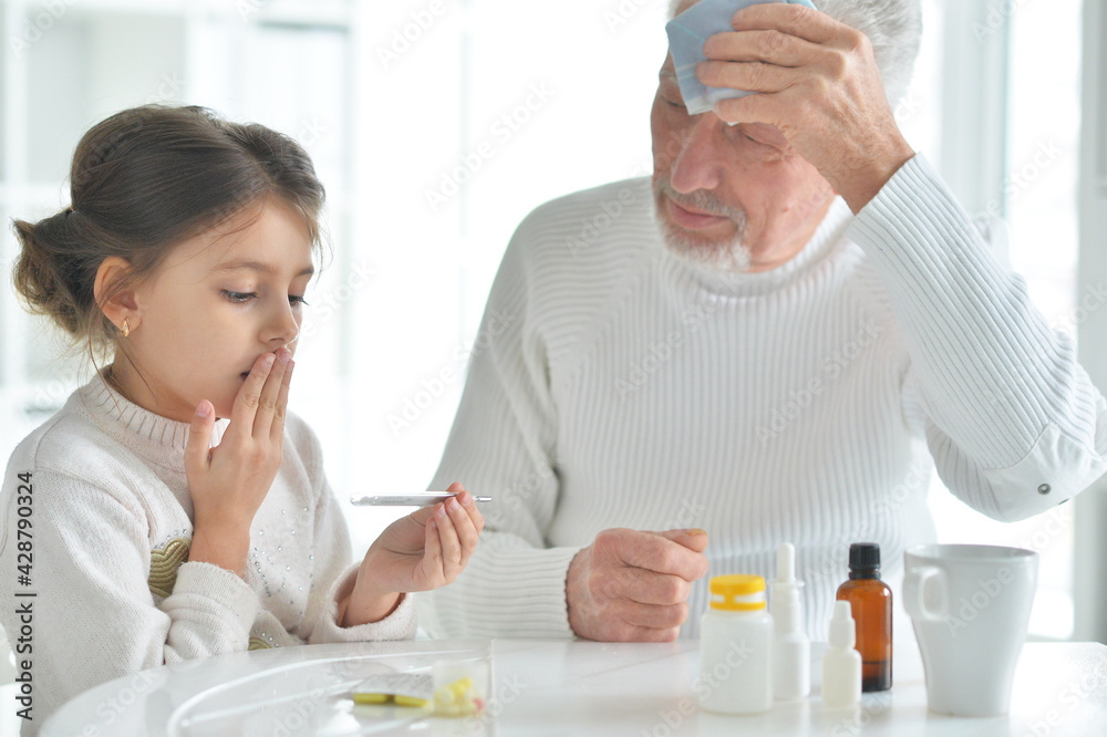 Granddaughter giving medicine to her grandfather in room Granddaughter giving medicine to her grandfather in room