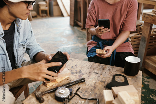 Carpenter phototgraphing wooden blocks for social media when having short coffee break in workshop