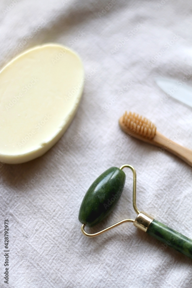 Jade face roller, wooden toothbrush, glass nail file and bar of soap. Sustainable body care products. Selective focus. Jade face roller, wooden toothbrush, glass nail file and bar of soap. Sustainable body care products. Selective focus.