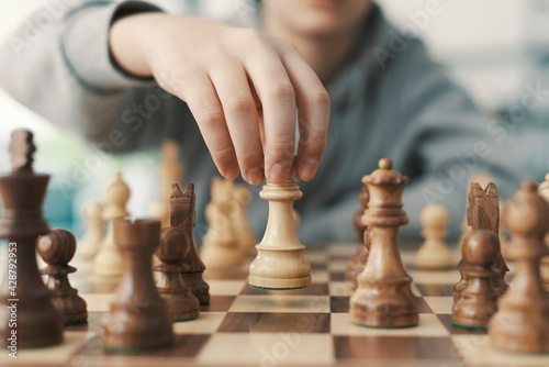 Boy playing chess and moving a piece