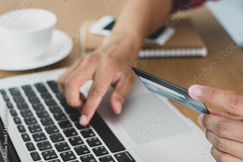 She hand typing on computer keyboard and hand holding a credit card to pay for items through an online payment system. Online shopping is the best option to reduce the spread of the coronavirus.