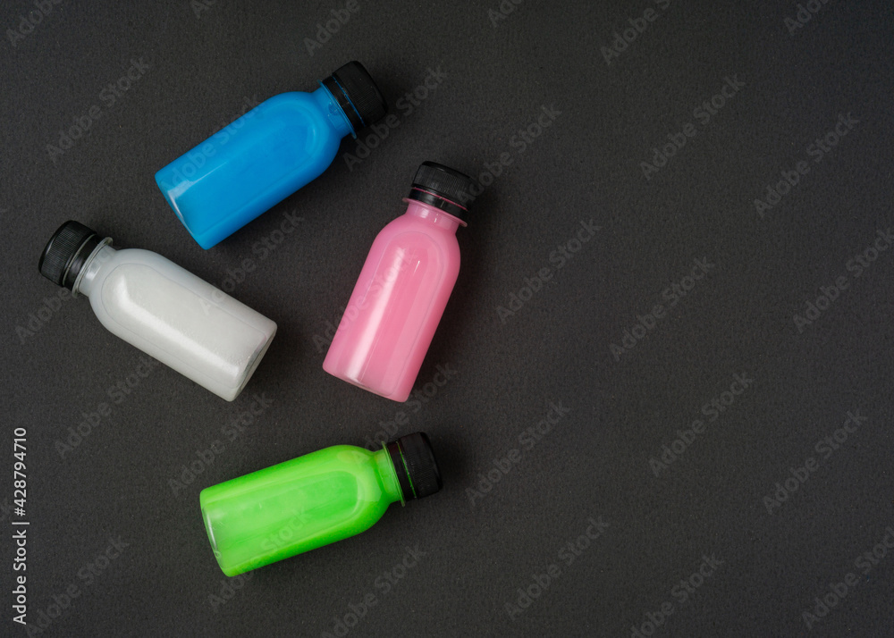Colorful liquid in a bottles on black background. Flat lay. Copy space. Colorful liquid in a bottles on black background. Flat lay. Copy space.