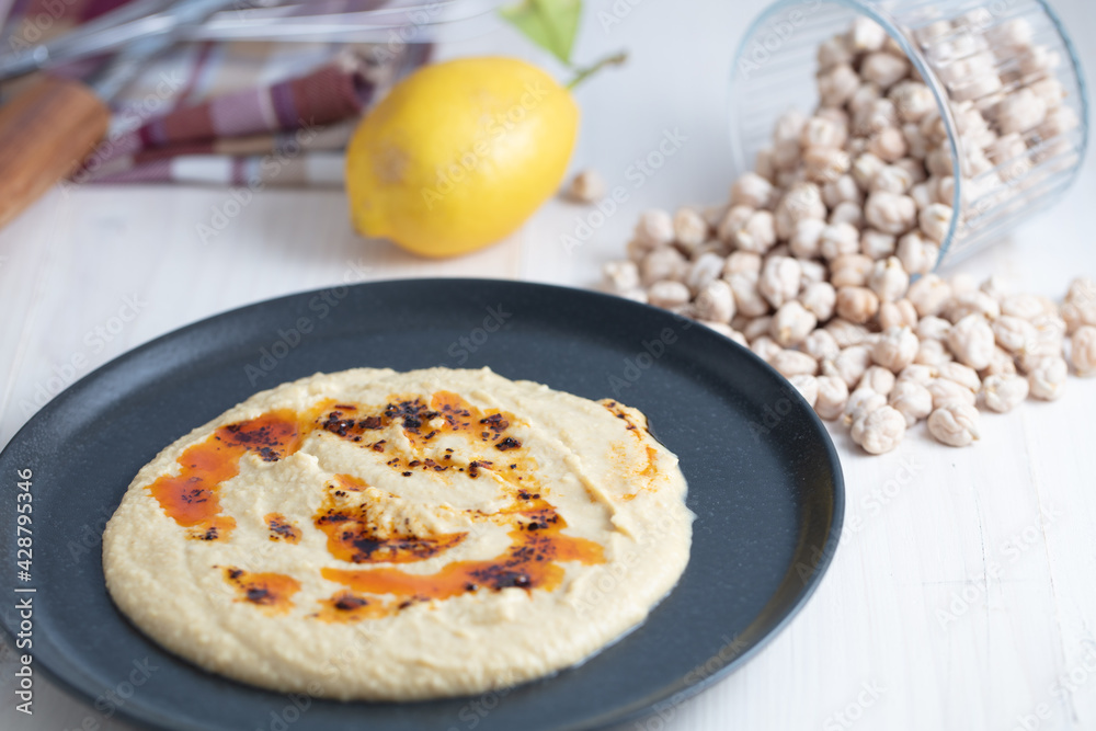 Home made hummus bowl, decorated with boiled chickpeas, lemon and olive oil over a rustic white background. Home made hummus bowl, decorated with boiled chickpeas, lemon and olive oil over a rustic white background.
