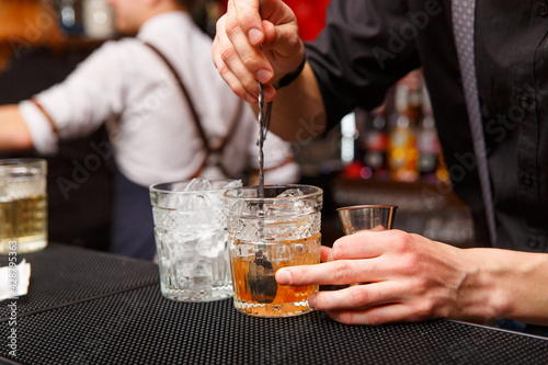 A male bartender uses spoon to mixing cocktail.