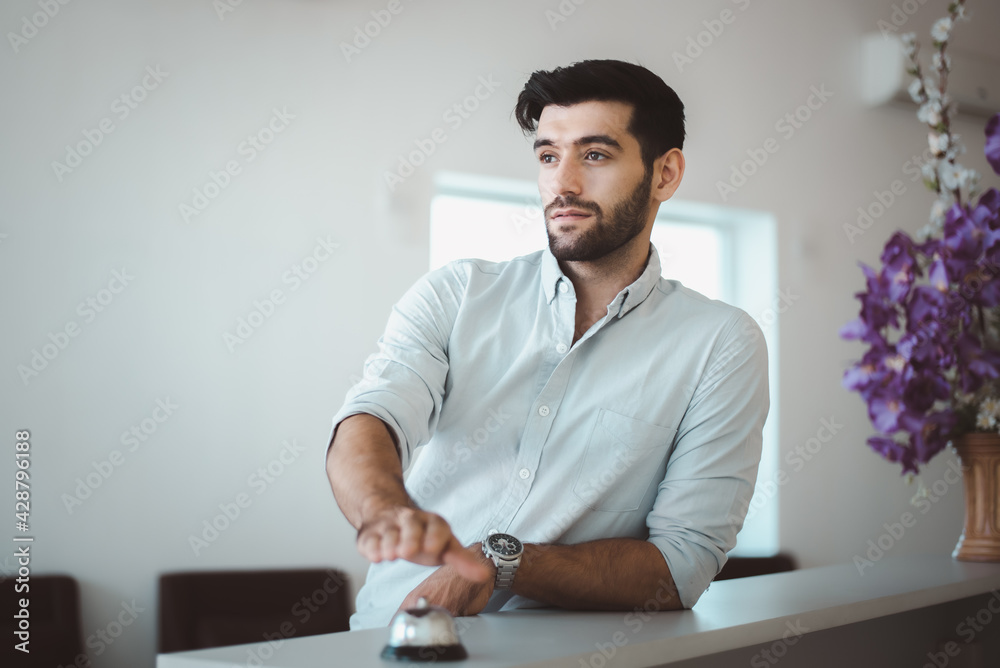 Fototapeta premium Business man using service bell on hotel reception desk.
