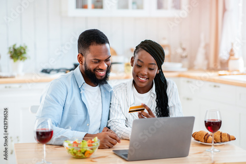 Black Couple Making Online Shopping With Laptop And Credit Card In Kitchen