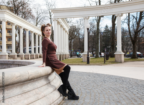 young woman posing sitting by a fountain on a city street