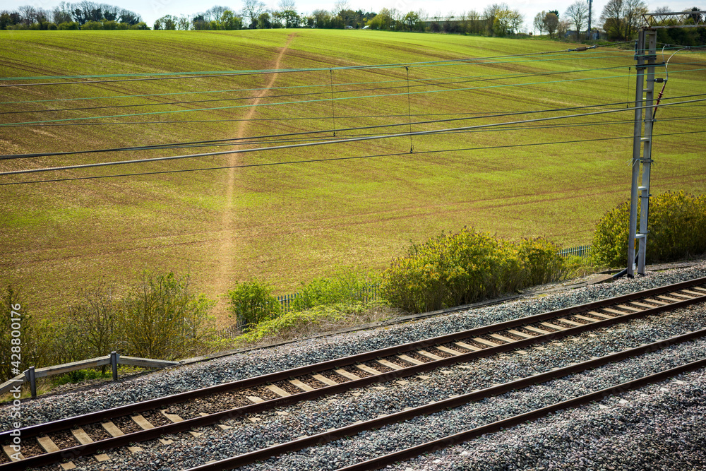 uk train railroad next to rapeseed field in bloom day view in england uk train railroad next to rapeseed field in bloom day view in england