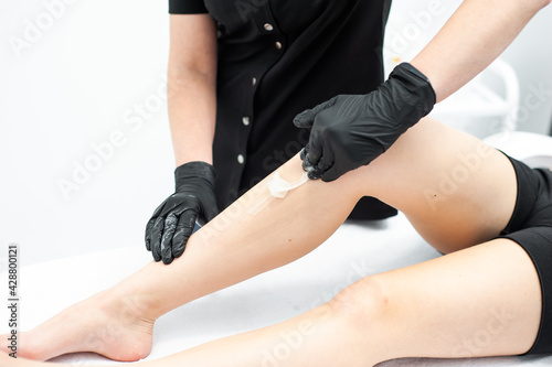 Midsection of female therapist waxing customer s leg at beauty spa