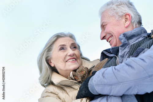 Happy senior couple hugging at snowy winter park