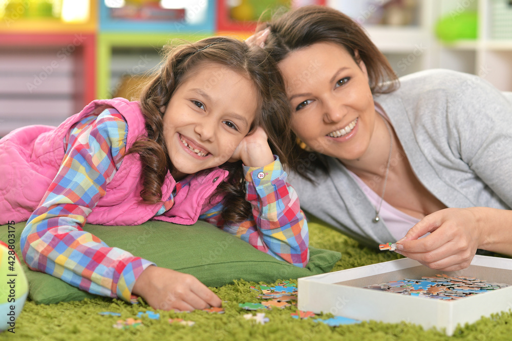 Fototapeta premium Mother with little daughter collecting puzzle