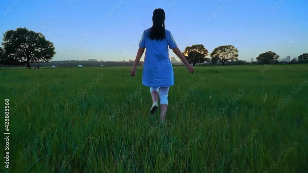 Girl running on green grass at dusk, opening her hands to enjoy beautiful nature Girl running on green grass at dusk, opening her hands to enjoy beautiful nature