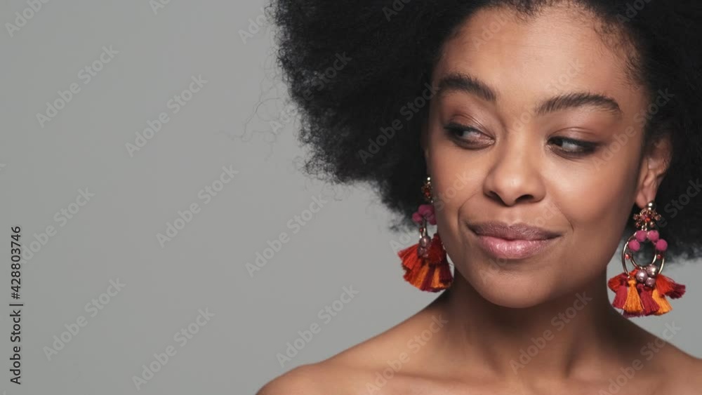 A close-up shot of the face of a smiling black woman pointing her eyes to the side in the studio