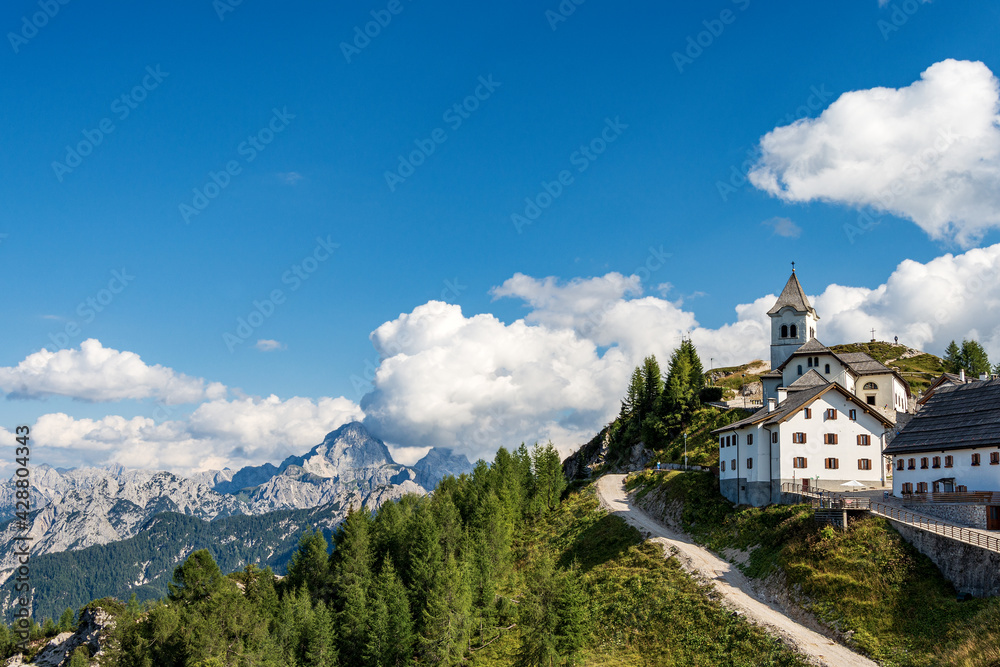 Small and ancient village of Lussari or Monte Santo di Lussari (1790 m) and the peak of Mangart mountain (2677 m.). Julian Alps, Tarvisio, Udine province, Friuli Venezia Giulia, Italy, Europe.