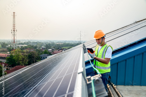 Engineer working on checking equipment in solar power plant. man working at solar roof paneled power station.engineers use tablet computer to examine solar panels installed solar panels using energy