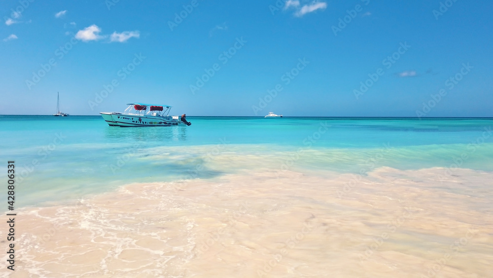 Ship floating in bright turquoise water. View of endless sea in tropical destination. Exotic vacation in Dominican Republic.