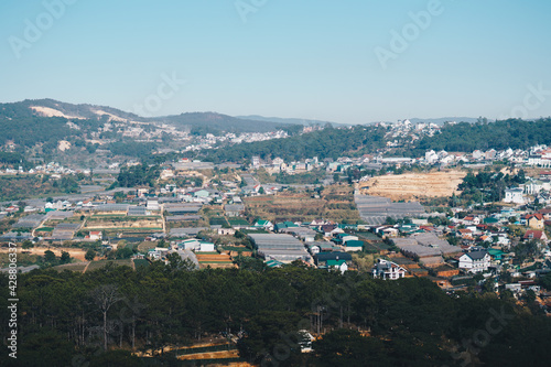 Panorama landscape, Dalat city, Langbian Plateau, Vietnam Central Highland region. Vegetable fields, many houses, architecture, farmlands, greenhouses. Forested Mountain background. Evening photo photo