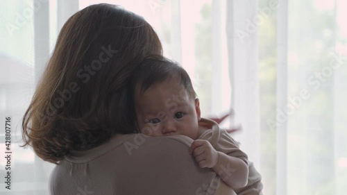 asian woman mother parent embracing baby infant lull and calm baby down near window at home. mom holding newborn baby with love and protection. kid trust parent.