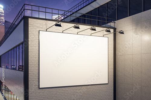 White blank outdoor billboard and lighting backlights on white brick wall of business center building at night. 3D rendering, mockup