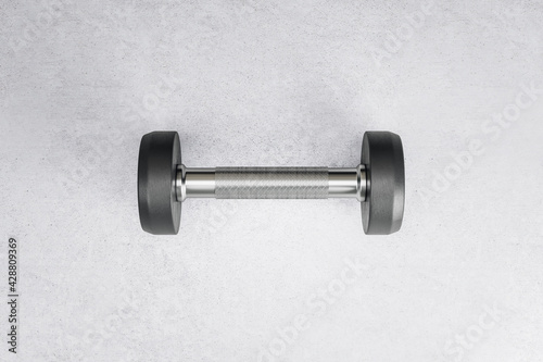 Sport and workout concept with stylish black dumbbell in the center of concrete floor backdrop