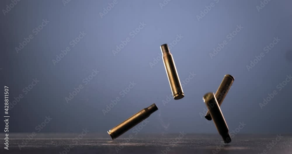 SUPER SLOW MOTION Empty machine gun shells falling on a ground against ...