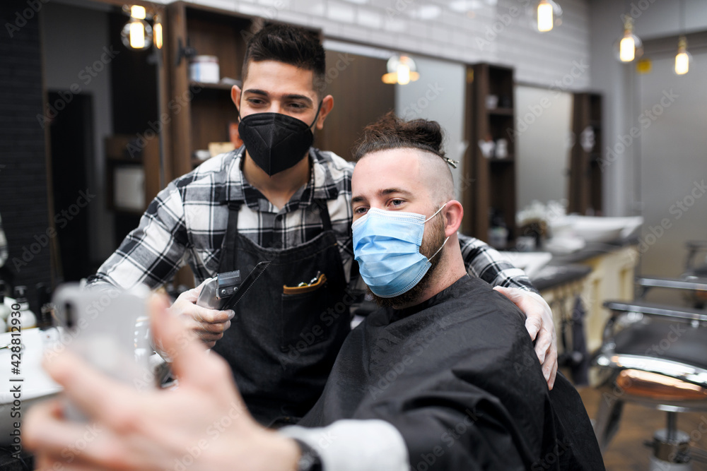 Man client taking selfie with haidresser in barber shop, coronavirus and new normal concept. Man client taking selfie with haidresser in barber shop, coronavirus and new normal concept.