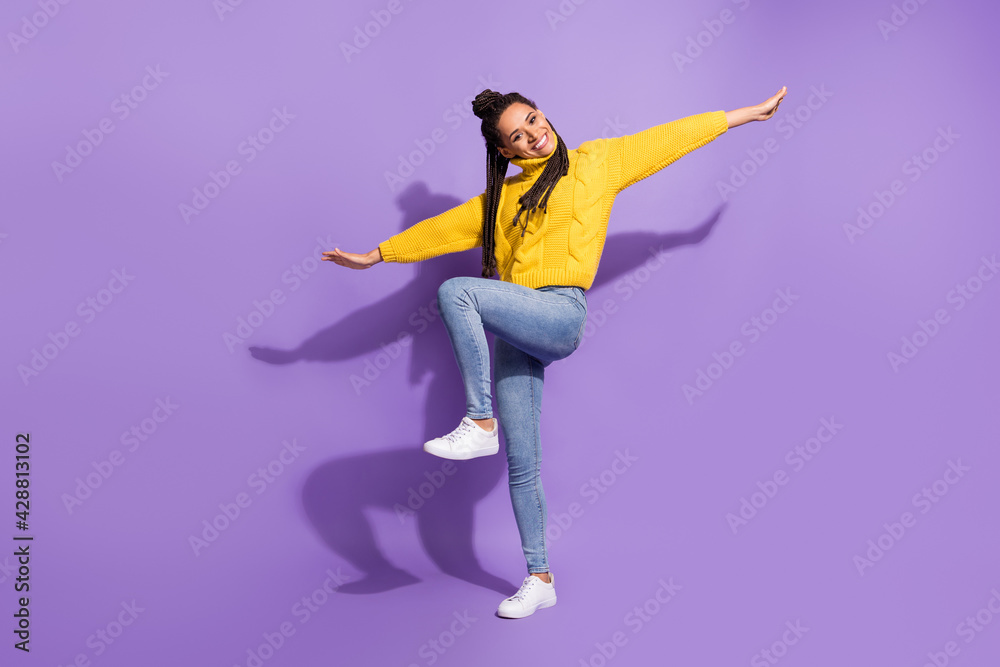 Obraz premium Photo portrait of funny girl standing on one pretending to be plane isolated on vivid purple colored background