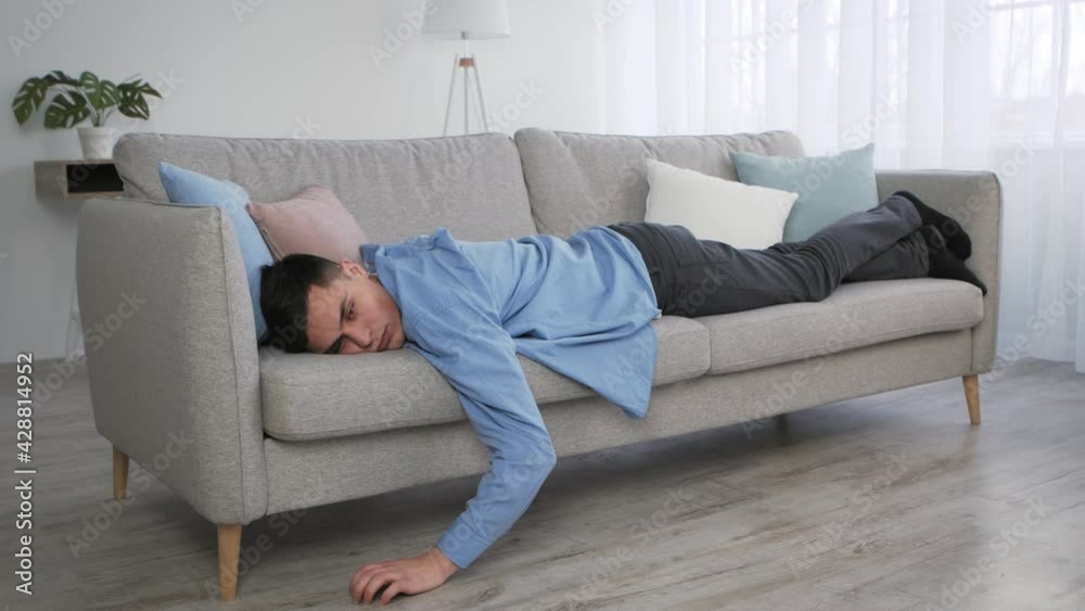 Apathy and disinterest. young depressed caucasian guy lying on sofa at home, feeling stress and indifference Apathy and disinterest. young depressed caucasian guy lying on sofa at home, feeling stress and indifference