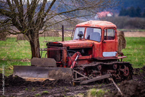 An old caterpillar bulldozer during work on leveling the ground. Made on a cloudy day  poor lighting conditions