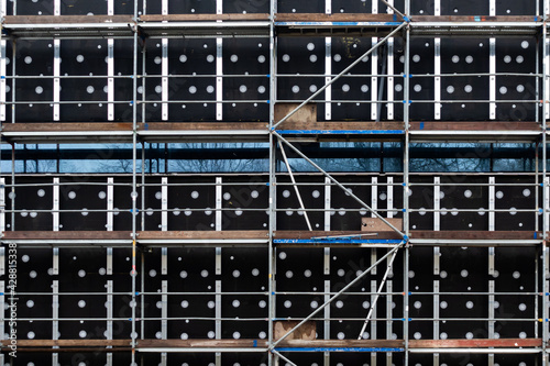 Scaffolding on the wall of a newly constructed public building. Photo taken in cloudy weather, late afternoon.