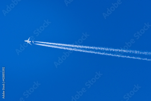 A passenger plane flies at high altitude and leaves a condensation trail behind it.