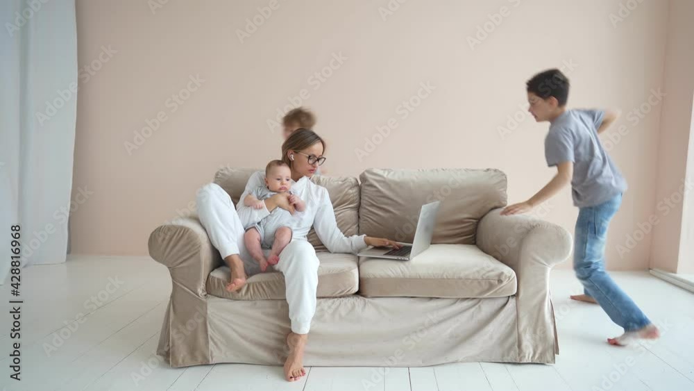 Not working atmosphere. Young woman trying to work on laptop, but her kids running around sofa and disturbing her. High quality 4k footage Not working atmosphere. Young woman trying to work on laptop, but her kids running around sofa and disturbing her. High quality 4k footage