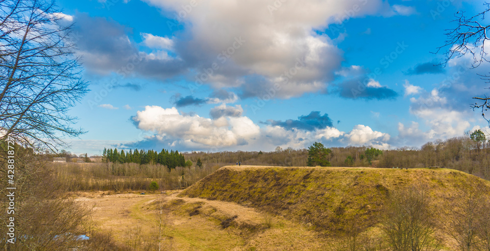 spring landscape of grassy mound and cloudy sky
